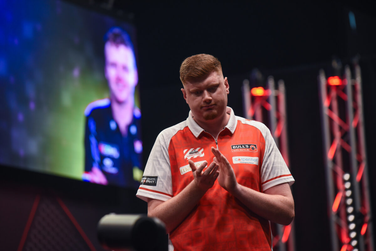 Niko Springer klatscht leicht Richtung Publikum, im Hintergrund Richard Veenstra auf der Leinwand.