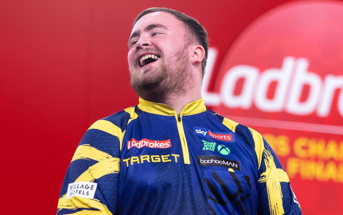 Luke Littler lachend auf der Bühne bei den Players Championship FInals